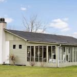 A house with large glass front and green fence in the garden.