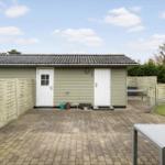 House with patio, fence, and garden. White doors and gray roof tiles.