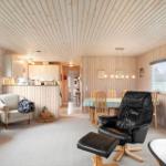 Living and dining area with wood paneling and black leather chair.
