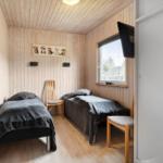 Two beds, wooden walls, window, and TV in a room.