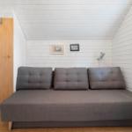 A gray sofa bed in a room with white walls and a window.