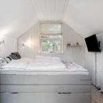 Bedroom with bed, window, and wall-mounted TV.