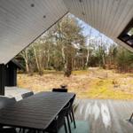 Deck with table, chairs, and grill under roof. View into the forest.