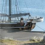 Segelschiff am Hafen mit Steuerrad und Rettungsring.