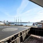 Blick vom Balkon auf Hafen mit Schiffen und Strand.