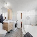 Badezimmer mit Badewanne, Waschmaschine und Toilette.
