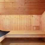 Holzsauna mit Sitzbank, Handtuch und Bürste. Heizung rechts.