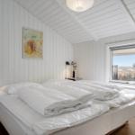 Schlafzimmer mit weißem Bett, Fenster und Holzboden.