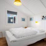 Schlafzimmer mit weißer Wandverkleidung, Bett, Fenster und gelber Lampe.