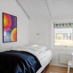 Schlafzimmer mit Bett, Fenster und Wandbild.