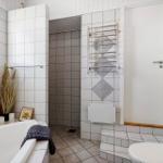 Badezimmer mit Badewanne, Dusche, Toilette und Fenster.
