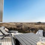 Terrasse mit Tisch, Stühlen und Liegestühlen. Blick auf trockenes Grasland unter blauem Himmel.