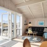 Wohnzimmer mit schwarzer Couch, runder Tisch und Blick auf Balkon.