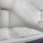 Schlafzimmer mit Dachschrägen, weißem Bett und Fenster mit Blick auf Dach