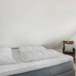Schlafzimmer mit Dachschrägen, Bett und Stuhl.
