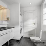 Badezimmer mit Waschbecken, Spiegel, Toilette und Waschmaschine