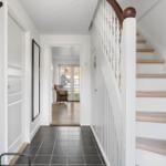 Hausgang mit Treppe und Tür. Durchgang zum Wohnzimmer mit Sicht auf Außentür.