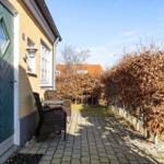 Haus mit grüner Tür, Terrasse und Garten mit Bäumen.