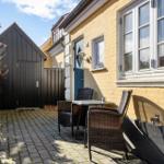 Hinterhof mit Tisch und Stühlen neben gelbem Haus mit blauer Tür.