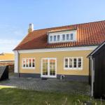 Haus mit gelbem Anstrich, rotem Dach und weißen Fenstern. Vorgarten mit Steinplatten.