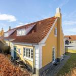 Gelbes Haus mit rotem Dach und kleinem Gartenbereich.