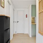 Hallway with black refrigerator, wooden floor, and view into the kitchen.