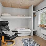 Bedroom with bunk bed, black leather chair, and window view of forest.