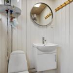 Bathroom with toilet, sink, and mirror on white panels.