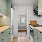 Kitchen with light cabinets, wooden countertops, and view into living area.