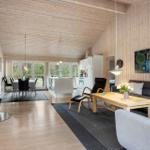Living and dining area with wood paneling, fireplace, and modern kitchen.