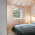 Bedroom with wooden walls, bed, and window overlooking the forest.