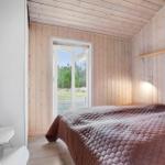 Bedroom with bed, wooden walls, and window to outdoor terrace.