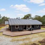 Modern wooden cabin with terrace and garden near forest.
