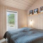 Bedroom with wooden walls, bed, and door to the garden.