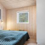 Bedroom with wooden walls, bed, and window to the forest.