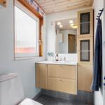 Bathroom with sink, mirror, toilet, and window.