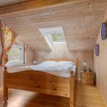 Bedroom with wooden walls, bed, window, and skylight.