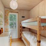A bedroom with a bunk bed, wooden walls, and a window.