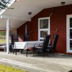 Patio with table and chairs in front of red wooden house