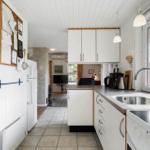 Kitchen with white countertop, sink, and window view of forest.