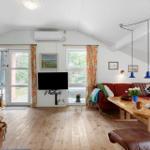 Living room with red sofa, wooden table, and TV. Wooden floor and white walls.