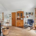 Living room with wood stove, wooden floor, and bookshelf on the wall.
