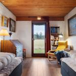 Zimmer mit zwei Betten, Bücherregal und Tür zum Garten.