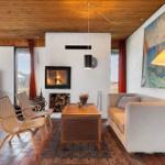 Wohnzimmer mit Kamin, Sofa, zwei Stühlen und Fernseher an der Wand.