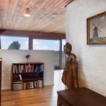 Raum mit Holzboden, Bücherregal, Statue und Wandbild mit Windmühle.
