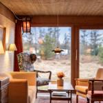Ein Wohnzimmer mit Sitzgelegenheiten und Blick auf einen Wald.