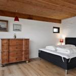 Schlafzimmer mit Holzboden, schwarzer Bettgestell und antikem Schrank.