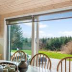 Dining area with view of lawn and forest through sliding door.