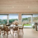 Dining area with table and chairs, sofa and large windows overlooking the garden.