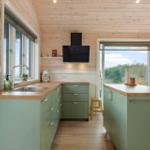 Kitchen with green cabinets, wooden surfaces, and view of the landscape.